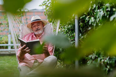 Happy senior man relaxing with book in the garden. - HPIF03708