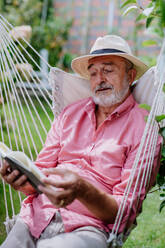 Happy senior man relaxing with book in the garden. - HPIF03709