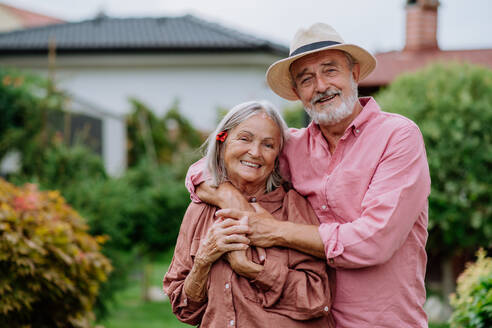 Verliebtes älteres Paar posiert zusammen in einem Garten. - HPIF03726