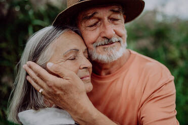 Portrait of senior couple in love, standing and hugging outdoor in the nature. - HPIF03738