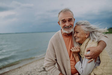 Ein älteres Paar entspannt sich und hat einen romantischen Moment am herbstlichen Meer. - HPIF03748