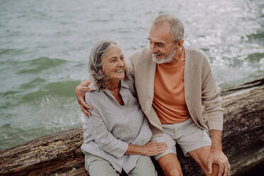 Ein älteres Paar sitzt und hat einen romantischen Moment am herbstlichen Meer. - HPIF03750