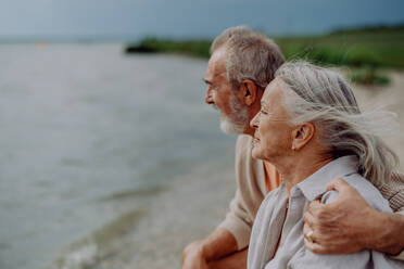 Älteres Paar, das sich entspannt und auf das herbstliche Meer blickt. - HPIF03756