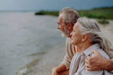 Senior couple relaxing and looking at autumn ocean. - HPIF03756