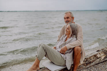 Senior couple sitting and having romantic moment at the autumn sea. - HPIF03758