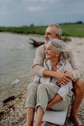 Senior couple sitting and having romantic moment at the autumn sea. - HPIF03759