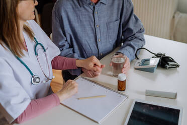 A close-up of doctor holding hand of senior patient and consoling him during medical visit at home. - HPIF03766