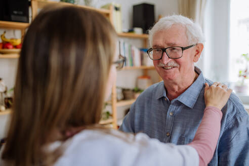 Eine Pflegekraft oder ein Pfleger besucht einen älteren Mann zu Hause. - HPIF03778
