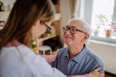 Eine Pflegekraft oder ein Pfleger besucht einen älteren Mann zu Hause. - HPIF03779