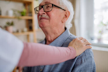 A healthcare worker or caregiver visiting senior man indoors at home. - HPIF03780