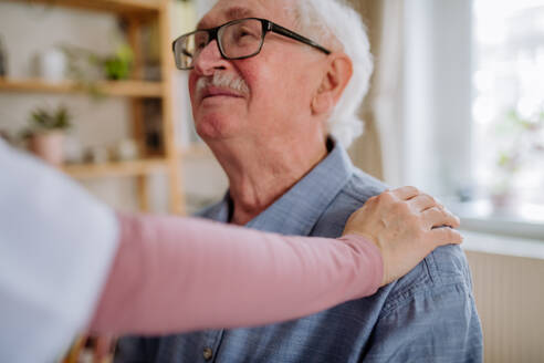 Eine Pflegekraft oder ein Pfleger besucht einen älteren Mann zu Hause. - HPIF03780
