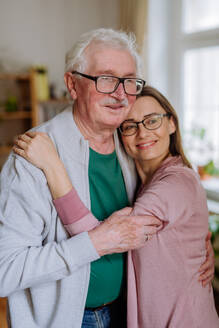 Eine erwachsene Tochter, die ihren älteren Vater umarmt, wenn sie ihn zu Hause besucht. - HPIF03790