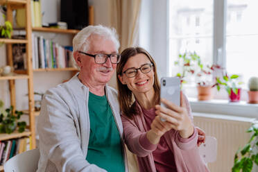 Eine erwachsene Tochter besucht ihren älteren Vater zu Hause und macht ein Selfie. - HPIF03795