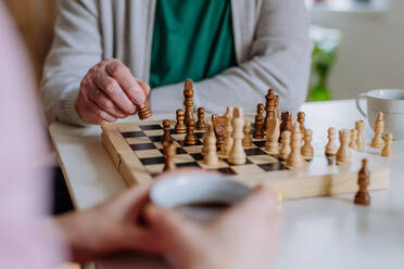 Nahaufnahme eines älteren Mannes, der mit seiner Tochter zu Hause Schach spielt. - HPIF03799