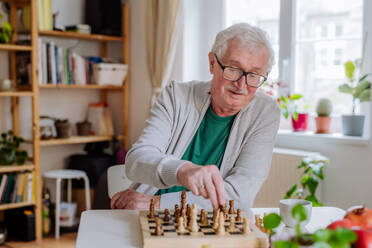 Ein älterer Mann spielt zu Hause Schach. - HPIF03800