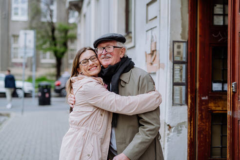 Eine erwachsene Tochter umarmt ihren älteren Vater, als sie ihn draußen auf der Straße trifft. - HPIF03804