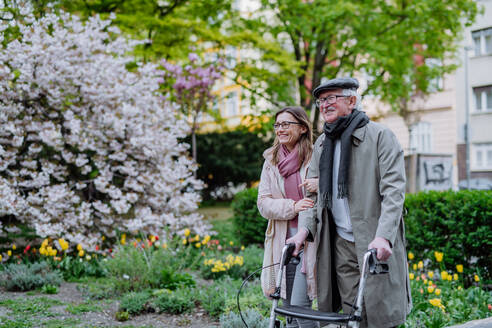 Ein älterer Mann mit Rollator und erwachsener Tochter bei einem Spaziergang im Park. - HPIF03806