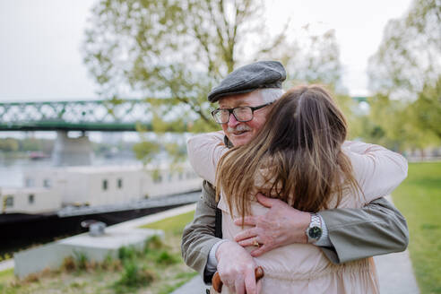 Eine Rückansicht einer erwachsenen Tochter, die ihren älteren Vater umarmt, als sie ihn auf der Straße trifft. - HPIF03822
