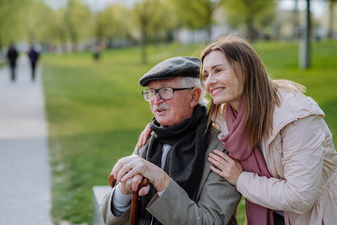 Ein glücklicher Senior mit seiner erwachsenen Tochter sitzt im Park. - HPIF03825