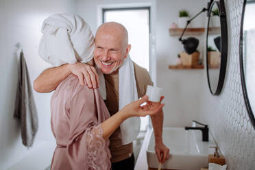 Ein älteres Ehepaar im Badezimmer, das sich die Zähne putzt und sich unterhält, Konzept der Morgenroutine. - HPIF03832