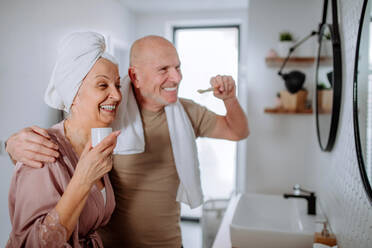 Ein älteres Paar im Badezimmer, Zähneputzen und Waschen, Spaß haben, Morgenroutine Konzept. - HPIF03834