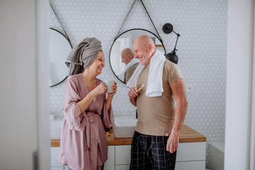 Ein älteres Ehepaar im Badezimmer, das sich die Zähne putzt und sich unterhält, Konzept der Morgenroutine. - HPIF03836