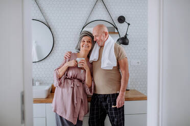 Ein älteres Ehepaar im Badezimmer, das sich die Zähne putzt und sich unterhält, Konzept der Morgenroutine. - HPIF03837