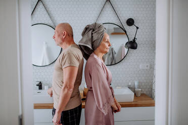 Ein älteres Paar im Badezimmer, Rücken an Rücken stehend, Konzept der Beziehungsprobleme. - HPIF03848