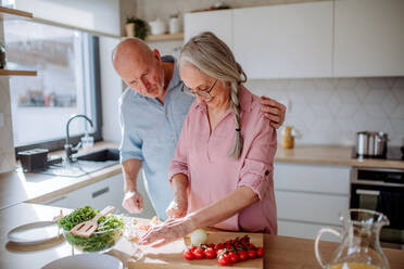Ein älteres Ehepaar kocht gemeinsam zu Hause. - HPIF03862