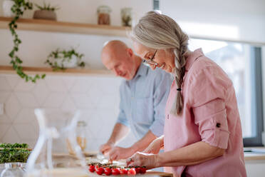 Ein älteres Ehepaar kocht gemeinsam zu Hause. - HPIF03863
