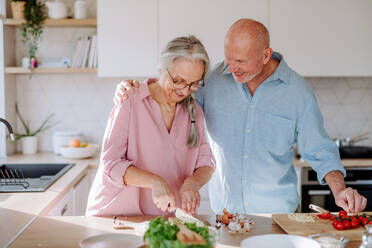 A senior couple cooking and smiling together at home. - HPIF03868