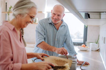 Ein älteres Ehepaar kocht gemeinsam zu Hause. - HPIF03872