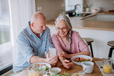 Ein glückliches Seniorenpaar beim gemeinsamen Abendessen zu Hause. - HPIF03878