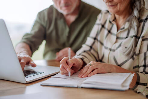 Nahaufnahme: Ein gestresstes älteres Ehepaar kalkuliert zu Hause gemeinsam Ausgaben oder plant das Budget. - HPIF03882