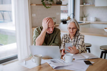 Ein gestresstes Seniorenpaar berechnet zu Hause gemeinsam Ausgaben oder plant das Budget. - HPIF03888