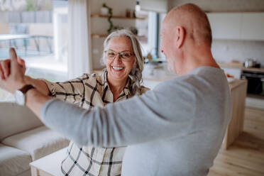 A cheerful senior couple dancing together at home. - HPIF03908