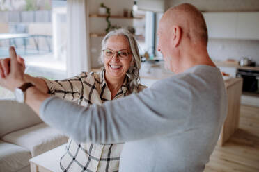 Ein fröhliches Seniorenpaar tanzt zusammen zu Hause. - HPIF03908
