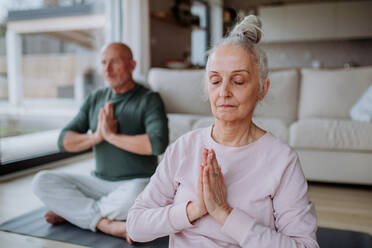 A senior couple doing relaxation exercise together at home. - HPIF03914