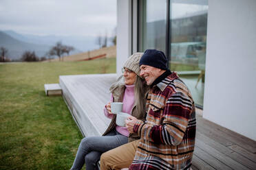 A happy senior couple sitting on terrace and drinking coffee together. - HPIF03918