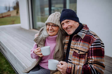Ein glückliches älteres Paar sitzt auf der Terrasse und trinkt gemeinsam Kaffee. - HPIF03919