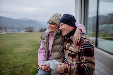 Ein glückliches älteres Paar sitzt auf der Terrasse und trinkt gemeinsam Kaffee. - HPIF03920