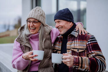 A happy senior couple sitting on terrace and drinking coffee together. - HPIF03921