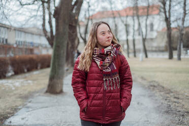 A young woman student with Down syndrome walking in street in winter - HPIF03926