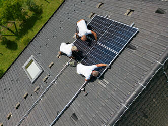 Hochformatige Ansicht eines männlichen Arbeiters bei der Installation von Solarzellen auf einem Dach, alternative Energie, Einsparung von Ressourcen und nachhaltiger Lebensstil. - HPIF03935