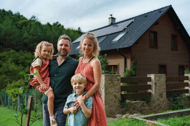 Glückliche Familie in der Nähe ihres Hauses mit Sonnenkollektoren. Alternative Energie, Ressourcenschonung und nachhaltiger Lebensstil. - HPIF03951