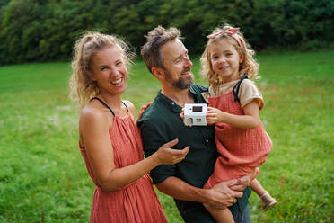 Little girl with her parents holding paper model of house with the solar panels.Alternative energy, saving resources and sustainable lifestyle concept. - HPIF03968