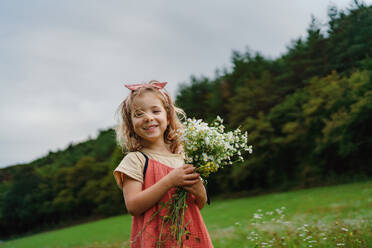 Kleines Mädchen in einem Sommerkleid pflückt Blumen auf einer Wiese. - HPIF03978