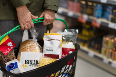Frau beim Einkaufen im Supermarkt, sie trägt einen vollen Einkaufskorb - HPIF04011