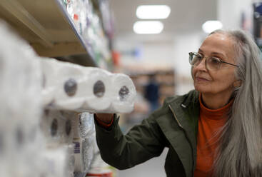 Eine ältere Frau kauft im Supermarkt Toilettenpapier. - HPIF04012