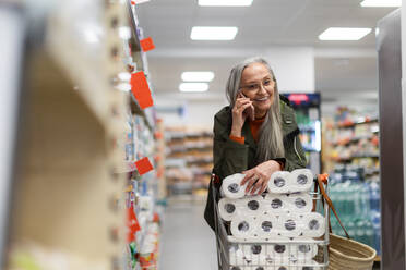 Eine ältere Frau kauft Toilettenpapier und ruft im Supermarkt an. - HPIF04014